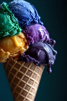 Colorful ice cream scoops in waffle cone featuring vibrant purple, blue, green, and orange flavors against dark background, macro food photography with melting details.
