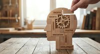 Hand placing wooden blocks with business growth concepts including gears and positive development terms on office desk for corporate strategy planning.