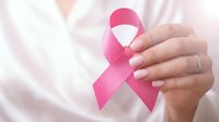 Woman holding pink ribbon symbol for breast cancer awareness campaign and healthcare support.