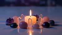 Burning candle surrounded by healing crystals and gemstones creating peaceful meditation atmosphere for wellness and spiritual practices.