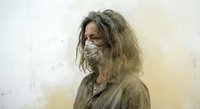 Disheveled middle-aged Caucasian man with long gray hair and face mask in dusty abandoned interior setting for apocalyptic survival horror concepts.