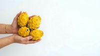 Hands holding fresh yellow custard apples or sugar apples isolated on white background, suitable for food, agriculture, and healthy eating designs.