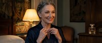 Mature Caucasian businesswoman smiling confidently in elegant home office setting with warm lighting and luxury decor for professional lifestyle content.