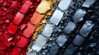 Crushed makeup eyeshadow palette texture showing gradient from red to gold and silver to black shades, with powder particles creating artistic pattern.