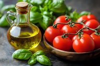 Fresh ripe tomatoes on vine in wooden bowl with extra virgin olive oil in glass bottle and green basil leaves on dark background, Mediterranean cuisine.