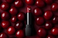 Red lipstick with heart pattern on top against background of glossy red cherries. Luxury cosmetic product photography for beauty and fashion marketing.