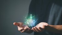 Business professional holding glowing digital brain with circuit patterns and light effects representing artificial intelligence and innovation technology.
