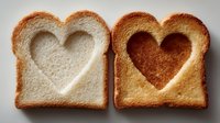 Two slices of toast with heart-shaped cutouts, one white bread and one golden brown, arranged side by side on gray background. Perfect for food blog or Valentine's Day concept.