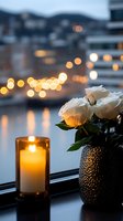 White roses in textured vase next to glowing candle on windowsill at dusk, with soft bokeh city lights creating romantic evening ambiance and reflections on water.