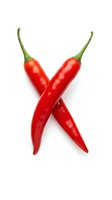 Two vibrant red chili peppers with green stems crossed in an X formation, isolated on white background. Perfect for culinary, food, and cooking design projects.