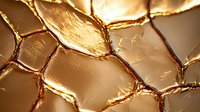 Metallic gold cracked surface with geometric pattern and textured details creates luxurious abstract background with light and shadow play.