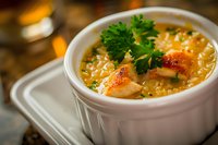 Creamy seafood chowder garnished with fresh parsley in white ceramic ramekin. Rich broth with tender shrimp, vegetables and potatoes creates warming comfort food.