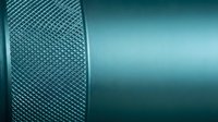 Turquoise metallic surface with textured knurled pattern detail. Industrial design background for modern technology and engineering applications.