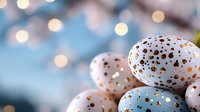 White and blue Easter eggs with gold metallic polka dot pattern on blurred bokeh background. Festive spring holiday composition with soft focus lighting effects.