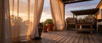Cozy outdoor terrace with flowing curtains and wooden deck at golden hour sunset creating warm ambiance for relaxation and entertaining guests.