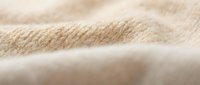 Soft beige knitted fabric texture with natural fibers showing detailed weave pattern for cozy home decor and fashion design projects.
