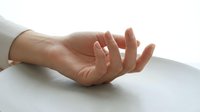 Open palm hand gesture on white surface showing relaxed fingers in natural light for wellness meditation and mindfulness concepts.
