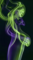 Abstract colorful smoke swirls in green and purple hues on black background for creative design projects and digital art compositions.