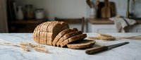 Freshly sliced whole grain bread loaf on wooden cutting board in rustic kitchen setting with wheat stalks, perfect for healthy eating and baking concepts.