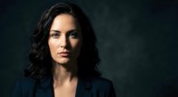 Professional businesswoman with dark wavy hair in navy blazer against dark background, confident corporate executive portrait for business marketing.