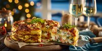 Festive layered potato gratin with herbs and bacon on wooden board, holiday dinner table setting with champagne glasses and Christmas tree lights.
