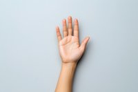 Raised open palm of a light-skinned person showing empty hand gesture against light gray background, representing greeting, voting, or volunteering concept.