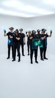 Group of diverse people wearing VR headsets experiencing virtual reality technology with holographic displays in modern white studio space for digital innovation.