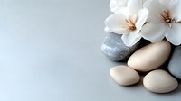 Serene spa composition with smooth pebbles and delicate white flowers on light background, creating peaceful wellness atmosphere for relaxation and meditation.