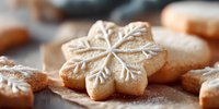Golden star-shaped gingerbread cookies with intricate white icing snowflake patterns dusted with powdered sugar on wooden surface for holiday baking.