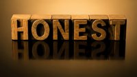 Wooden letter blocks spelling HONEST with dramatic lighting and reflection on dark surface for business ethics and integrity concepts.