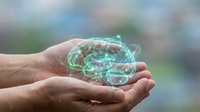 Hand holding glowing digital brain hologram with neural network connections, representing artificial intelligence, technology innovation, and futuristic computing solutions.