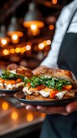 Gourmet sandwich with roasted vegetables, fresh arugula, and melted mozzarella on artisanal bread served by waiter in restaurant with warm ambient lighting.