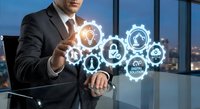Professional businessman in dark suit touching glowing digital security icons with gears and locks in modern office environment for cybersecurity concepts.
