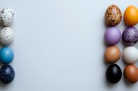 Colorful Easter eggs in modern pastel and natural tones arranged in minimalist composition on light background, creating negative space for text placement.