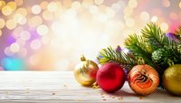 Festive Christmas ornaments and pine branches on wooden surface with colorful bokeh background for holiday greeting cards and seasonal decorations.