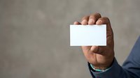 Man holding blank white business card in hand against neutral background. Male professional displaying empty card for branding and corporate identity mockup purposes.