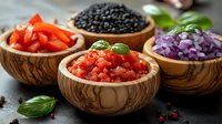 Fresh chopped vegetables and black caviar in wooden bowls with basil leaves on dark background, colorful ingredients for healthy cooking and garnish.