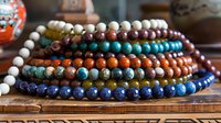 Colorful gemstone bead bracelets stacked on wooden surface showcasing natural stone jewelry collection for meditation, healing and fashion accessories.