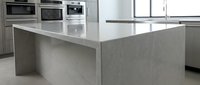 Modern kitchen with concrete island countertop and stainless steel appliances, suitable for interior design, home renovation, and architectural projects.