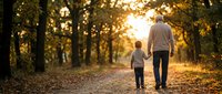 Father and son walking together on autumn path through golden forest during sunset creating warm family bonding moment for parenting and relationship concepts.