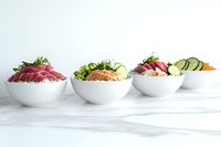 Fresh poke bowls with raw tuna, salmon, and vegetables served in white ceramic bowls on marble surface, healthy Asian cuisine presentation.