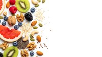 Healthy breakfast ingredients with fresh fruits, nuts, seeds and oats on white background. Nutritious superfood mix for morning meal preparation.