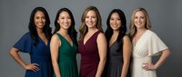 Five diverse professional women in elegant business attire standing together, representing teamwork and corporate success in modern workplace.