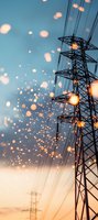 Power transmission tower silhouette against sunset sky with glowing bokeh lights and electrical wires creating magical atmosphere during golden hour.