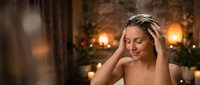 Young Caucasian woman relaxing at luxury spa with candles and warm lighting, enjoying peaceful wellness treatment and self-care moment.
