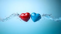 Red and blue heart shapes floating with dynamic water splash and droplets against turquoise background, romantic concept for valentines and relationships.
