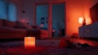 Romantic evening atmosphere with glowing candle and red rose on carpet, moody orange lighting creates intimate ambiance in cozy living room interior.