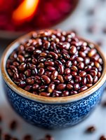 Fresh adzuki beans in blue ceramic bowl with traditional pattern. Macro shot of red beans showing natural texture and shine for cooking and food design.