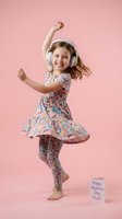 Happy young girl dancing with headphones in floral dress on pink background celebrating mothers day with greeting card for family holiday concepts.