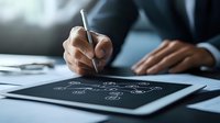 Professional drawing on digital tablet with stylus pen, creating mind map or business strategy diagram in modern office environment. Focus on hand detail.